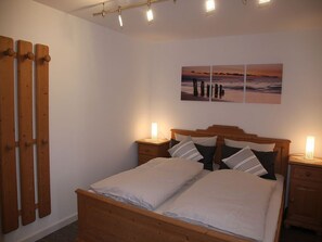 Ein Schlafzimmer mit einem hölzernen Bett, zwei Nachttischen mit Lampen, einem an der Wand hängenden Kunstwerk und einem Holzschrank.
