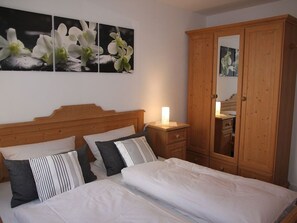 Une chambre avec un lit en bois, une table de chevet, une armoire et des œuvres d’art murales.