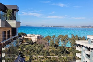 Blick auf die Küste vom Balkon über türkisfarbenem Meer und eine Stadtansicht.
