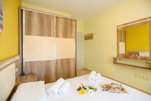 A hotel room with a bed, a wooden wardrobe, a mirror, and a magazine on the bed. - 307 B, Sea View One Bedroom Apartment, Vlore, Albania (Vlore)