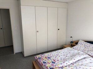 A bedroom with a bed, a nightstand, a wardrobe, and a door. - Casa Pignia - Roth, (Laax GR), by Interhome (Laax)