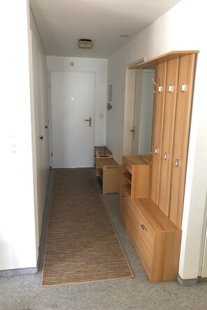 A hallway with a wooden wardrobe, a mirror, and a door. - Casa Pignia - Roth, (Laax GR), by Interhome (Laax)