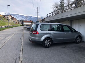 Een zilveren auto geparkeerd op een straat met een bergachtig decor.