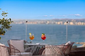 A balcony with two drinks, a city view, and a chair with a cushion. - 203 B, One Bedroom Apartment, Vlore, Albania (Vlore)