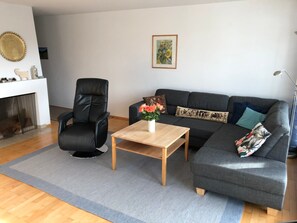 A living room with a black leather chair, a grey sofa, a wooden coffee table, and a vase of flowers. - Capol-Garten, (Flims Dorf), 2567 by Interhome (Flims)