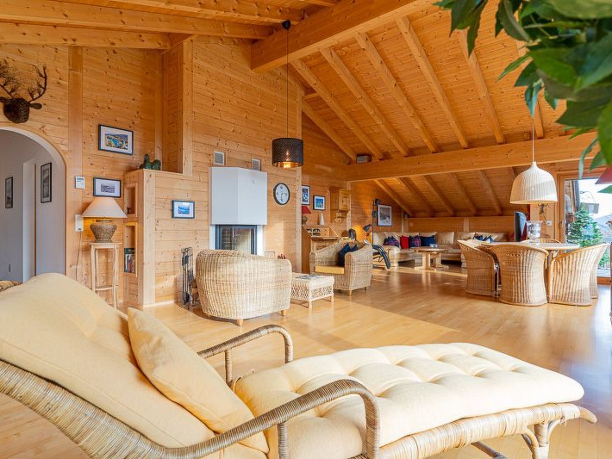 Ruime houten inrichting met een hoge plafond, rieten meubels en een open haard.