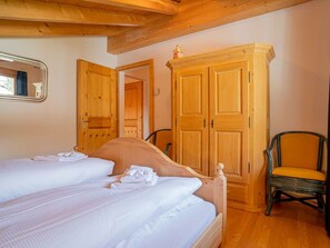 A bedroom with two beds, wooden wardrobes, and a chair. - Mira Flem, (Flims Dorf), by Interhome (Flims)