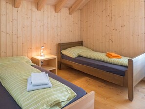 A wooden cabin room with two beds, a nightstand, and a lamp. - Caflisch Jacob und Erika, (Trin Mulin), 500 by Interhome (Trin)