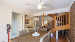Ein Essbereich mit Holztisch, Stühlen, Deckenventilator und einer Treppe.