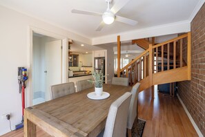 Ein Essbereich mit Holztisch, Stühlen, Deckenventilator und einer Treppe.