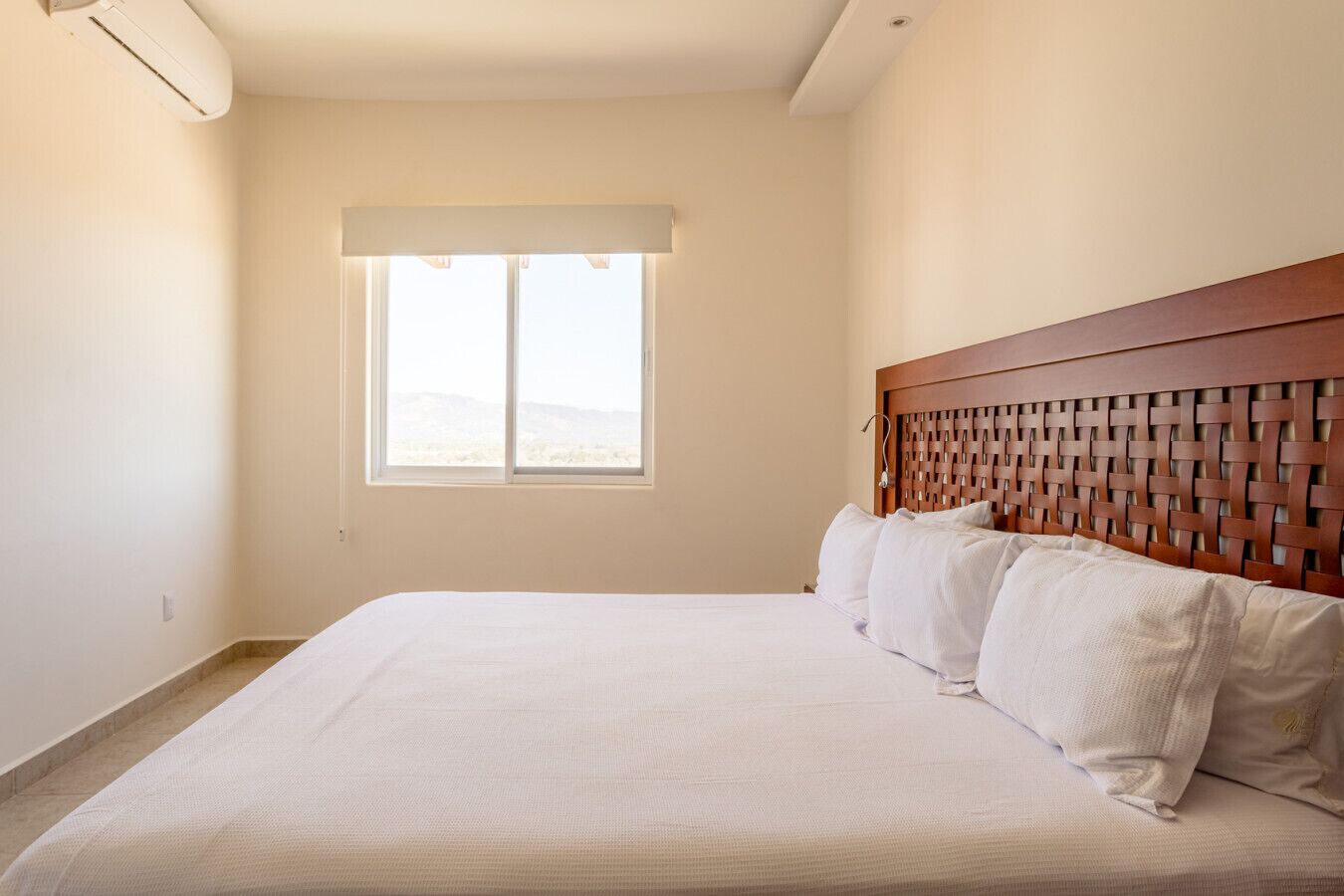 Una habitación de hotel con una cama grande, un ventanal con vistas y un cabecero de madera.