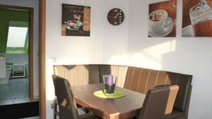 A dining area with a wooden table and chairs, a clock on the wall, and a framed picture above the table. - MeerZeit by Interhome (Rehburg)