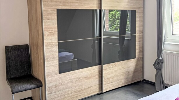 A room with a large wardrobe, a chair, and a window with curtains. - MeerZeit by Interhome (Rehburg)
