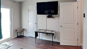 Una habitación con un televisor montado en la pared, un banco y dos puertas.