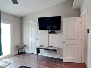 A room with a television mounted on the wall, a bench, and two doors. - Palms at Cove View 612 - Gulf Gazing (Galveston)