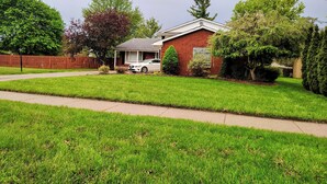 A single-story house with a front yard, a car parked in the driveway, and a wooden fence. - Step into The Guest House… stay awhile, where comfort meets elegance. (Inkster)