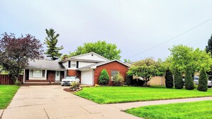 A two-story house with a garage, a driveway, and a well-maintained lawn. - Step into The Guest House… stay awhile, where comfort meets elegance. (Inkster)