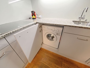 A compact kitchen with a built-in washing machine, a countertop, and a sink. - Apartment  by Interhome (Zurich)