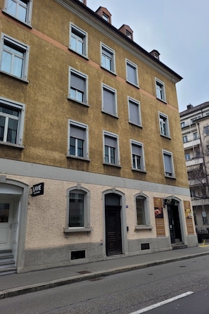 Ein mehrstöckiges Gebäude mit einem Eingang im Erdgeschoss, auf dem 'LAVIE CONFUITE' steht.