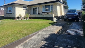 A two-story house with a tiled roof, a chimney, and a paved driveway.