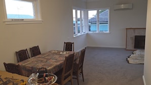 A dining area with a table set for four, a fireplace, and large windows with a view.