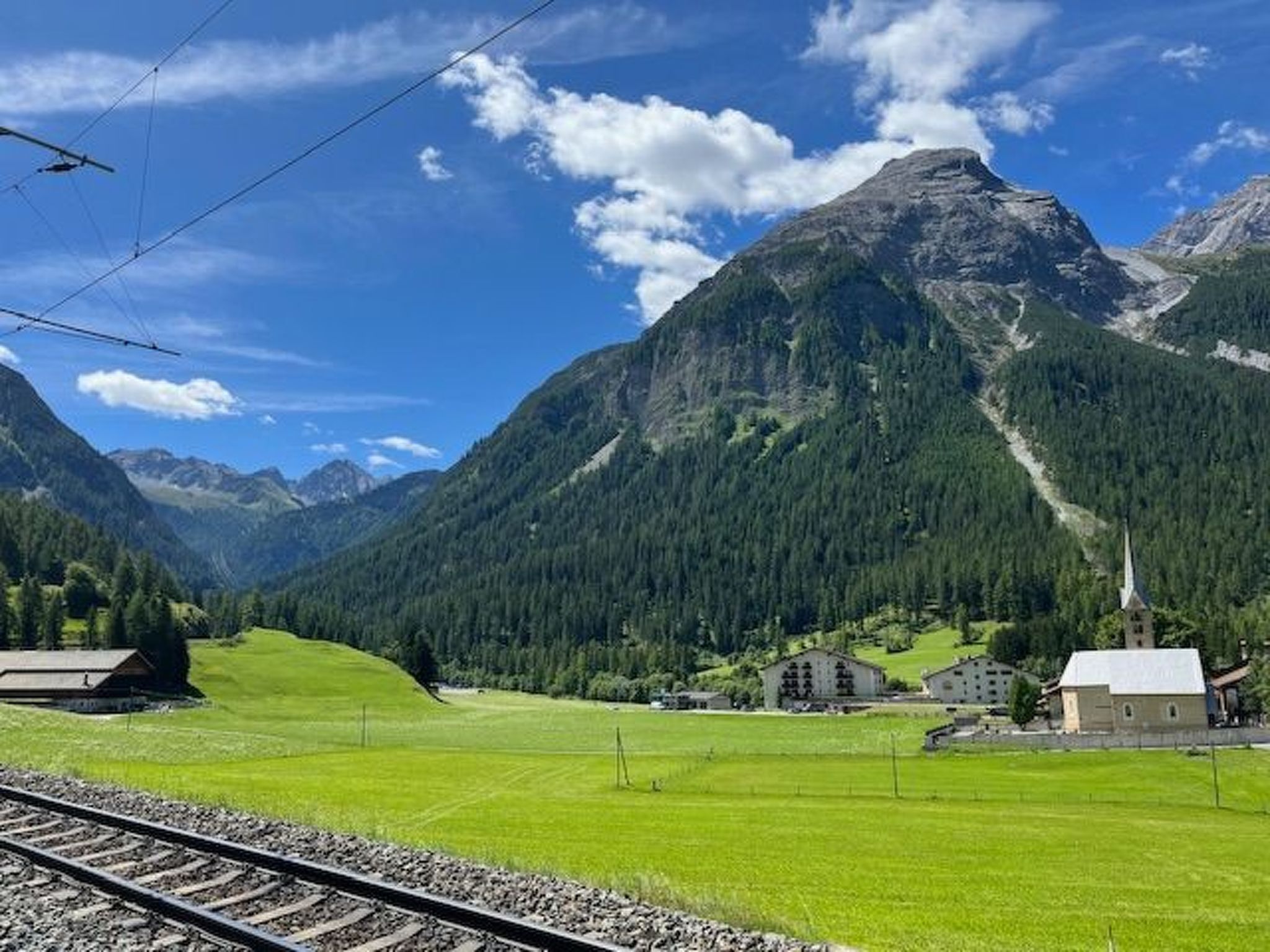 Un paysage montagneux avec une église et des bâtiments situés dans une vallée.