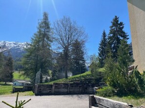 Un paysage montagneux avec un ciel dégagé, une clôture en bois et un petit bâtiment au premier plan.