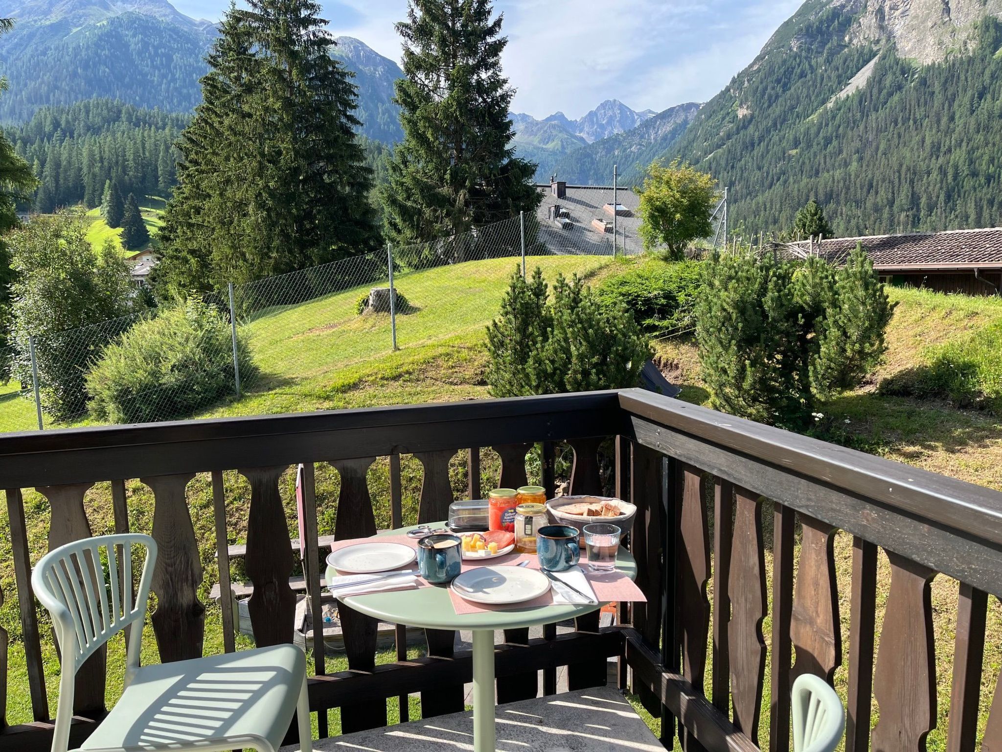 Eine Holzterrasse mit gedecktem Tisch, mit Blick auf eine Berglandschaft.