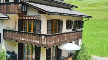 Un immeuble de deux étages doté d’un balcon, de grandes fenêtres et offrant une vue sur un paysage verdoyant.