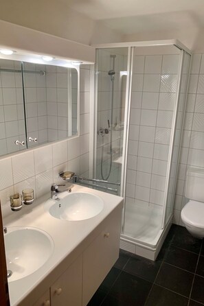 A bathroom with two sinks, a glass-enclosed shower, and a toilet. - Tga Clavo°, (Filisur), 117 by Interhome (Filisur)