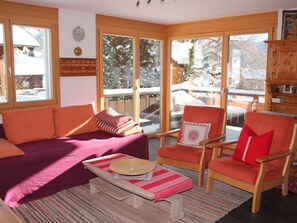 Una sala de estar acogedora con un sofá, sillones y una mesita de centro.