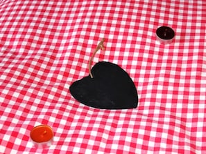 A checkered tablecloth with a black heart-shaped object and two candles. - Huggel, (Camischolas/Sedrun), 228.01 by Interhome (Camischolas)