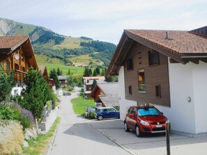 Ein Wohngebiet mit Holzhäusern, einer gepflasterten Straße und einer bergigen Landschaft im Hintergrund.