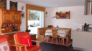 En hyggelig stue med pejs, et spiseområde med bord og stole, og et køkkenområde med komfur og skabe.