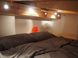 A bedroom with a bed, a wall-mounted fan, and a red lamp. - Mira Piz Signina, (Laax Dorf), 37024 by Interhome (Laax)