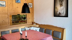 Ein Essbereich mit kariertem Tischläufer, Holzbänken und einem gerahmten Bild an der Wand.