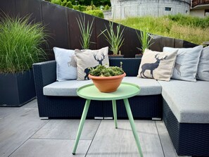 A modern outdoor seating area with a sofa, cushions, and a potted plant. - Mira Piz Signina, (Laax Dorf), 37024 by Interhome (Laax)