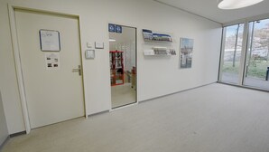 Un couloir avec une porte, un tableau d’affichage et une fenêtre donnant sur un paysage.