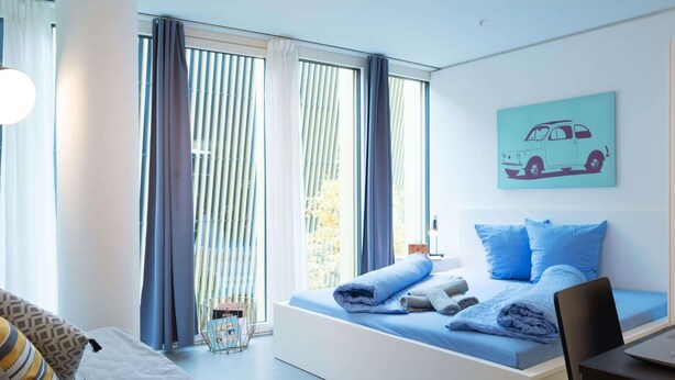 Une chambre moderne avec un lit, un bureau et une fenêtre avec des rideaux.