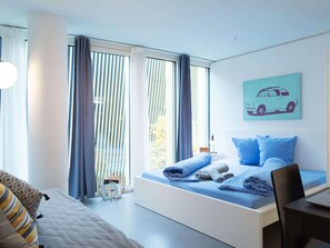 Ein modernes Schlafzimmer mit Bett, Schreibtisch und einem Fenster mit Vorhängen.