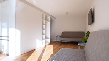 A modern living room with a sofa, a coffee table, and a television mounted on the wall.
