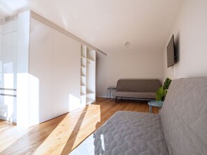 A modern living room with a sofa, a coffee table, and a television mounted on the wall. - Apartment  by Interhome (Basel)