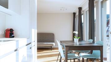 A modern kitchen with white cabinets, a red appliance, and a dining area with a wooden table and chairs.