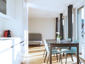 Eine moderne Küche mit weißen Schränken, einem roten Gerät und einem Essbereich mit einem Holztisch und Stühlen.
