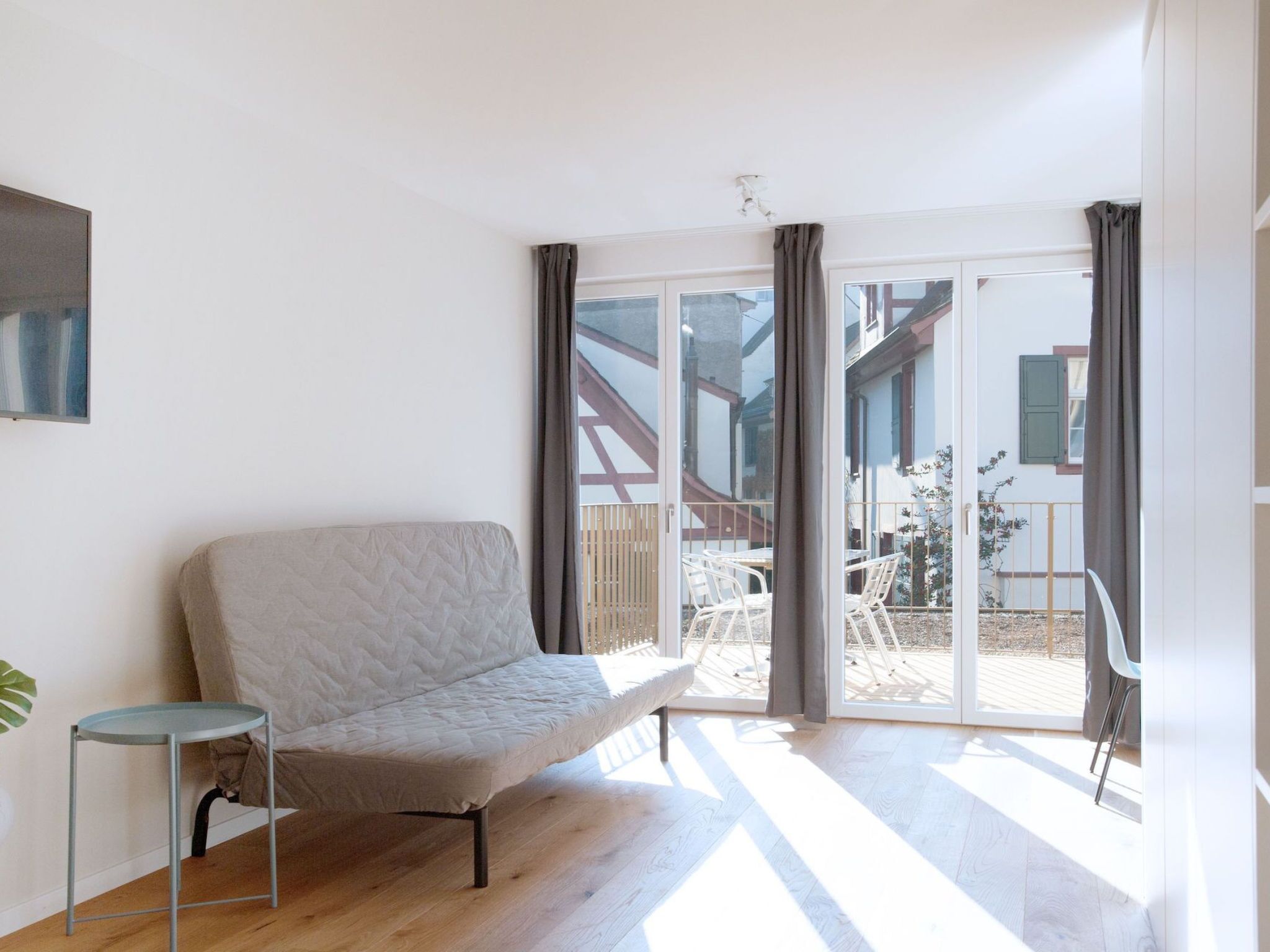 Ein modernes Wohnzimmer mit einer Couch, einem kleinen Tisch und einer Schiebetür zu einer Terrasse.
