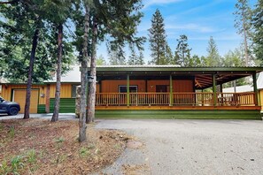 Eine Lodge mit überdachter Veranda, einer Garage und einer Auffahrt.