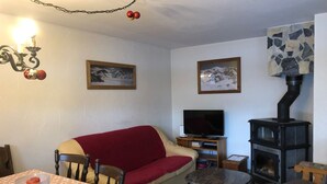 Ein gemütliches Wohnzimmer mit einer Couch, einem Fernseher, einem Kamin und einem Tisch mit kariertem Tischläufer.