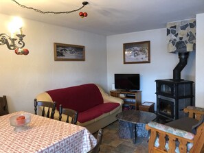 Ein gemütliches Wohnzimmer mit einer Couch, einem Fernseher, einem Kamin und einem Tisch mit kariertem Tischläufer.
