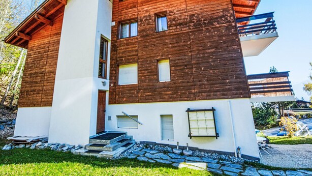 Ein modernes, zweistöckiges Gebäude mit Holzfassade und weißem Unterteil.