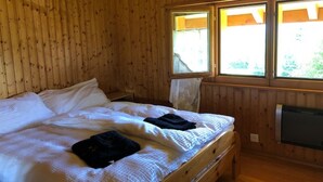 Ein Zimmer mit Holzboden, einem Bett, einem Fenster und einem Heizgerät.